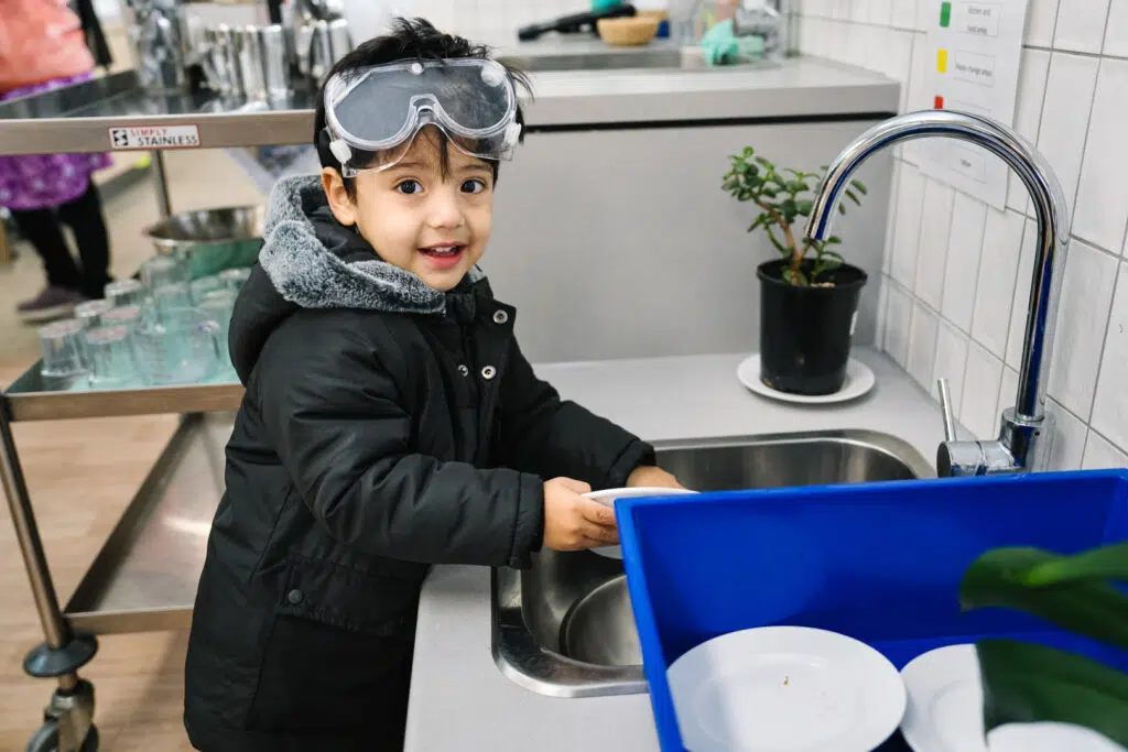 Child washing their plate at KU Maidstone childcare