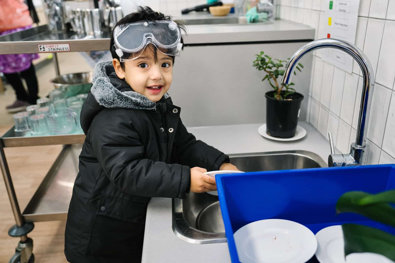 Child washing their plate at KU Maidstone childcare