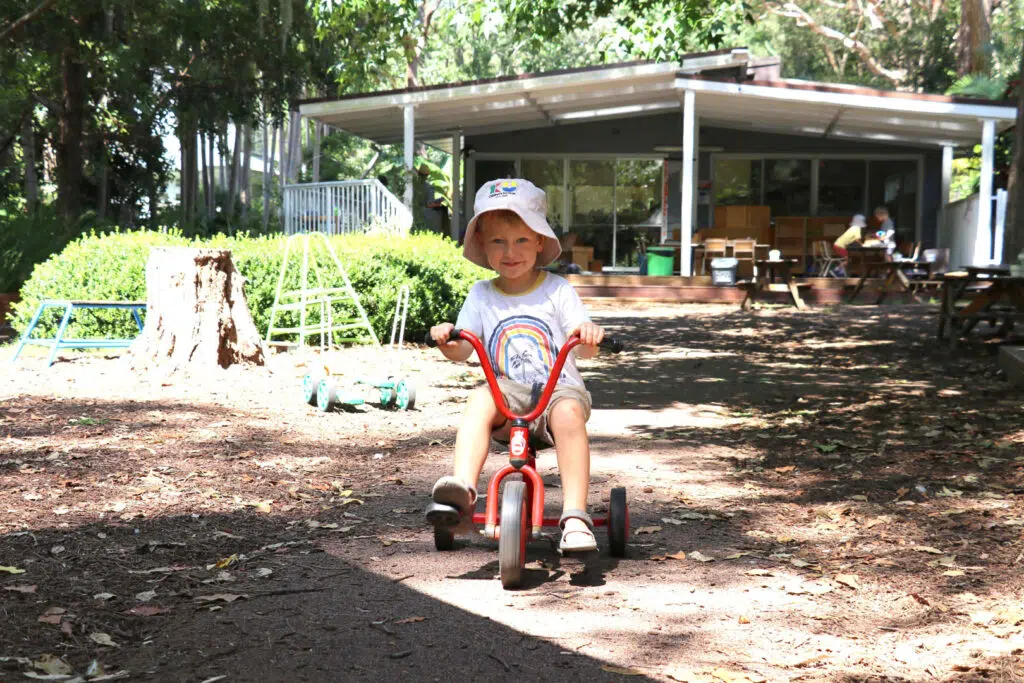 Child riding a tricycle at KU Avalon childcare