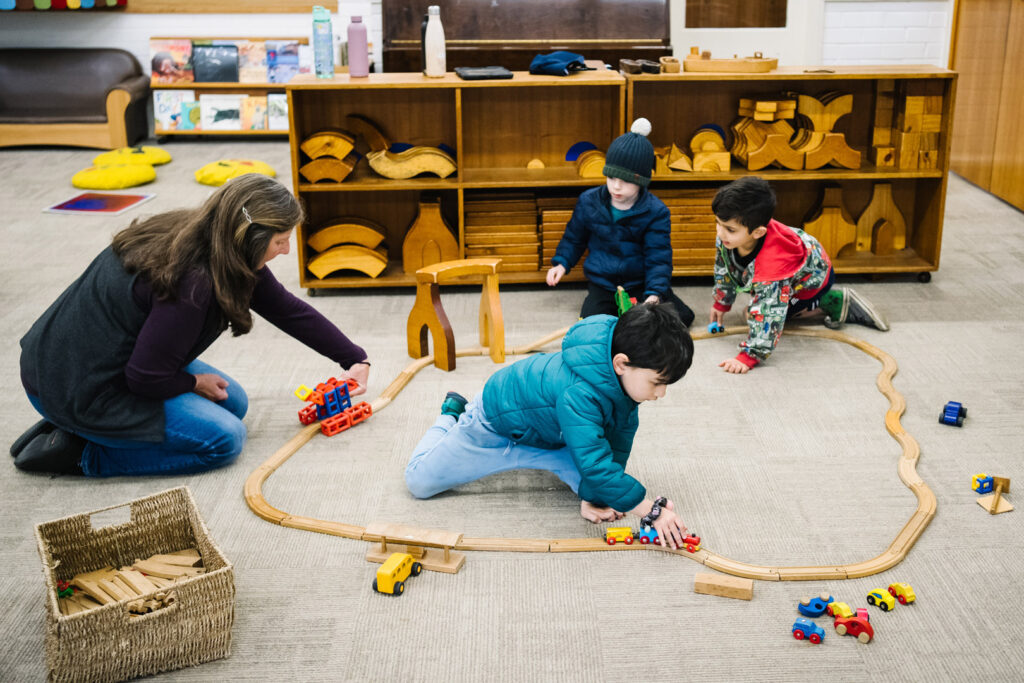 KU Berowra childcare educator playing with children and trainsets