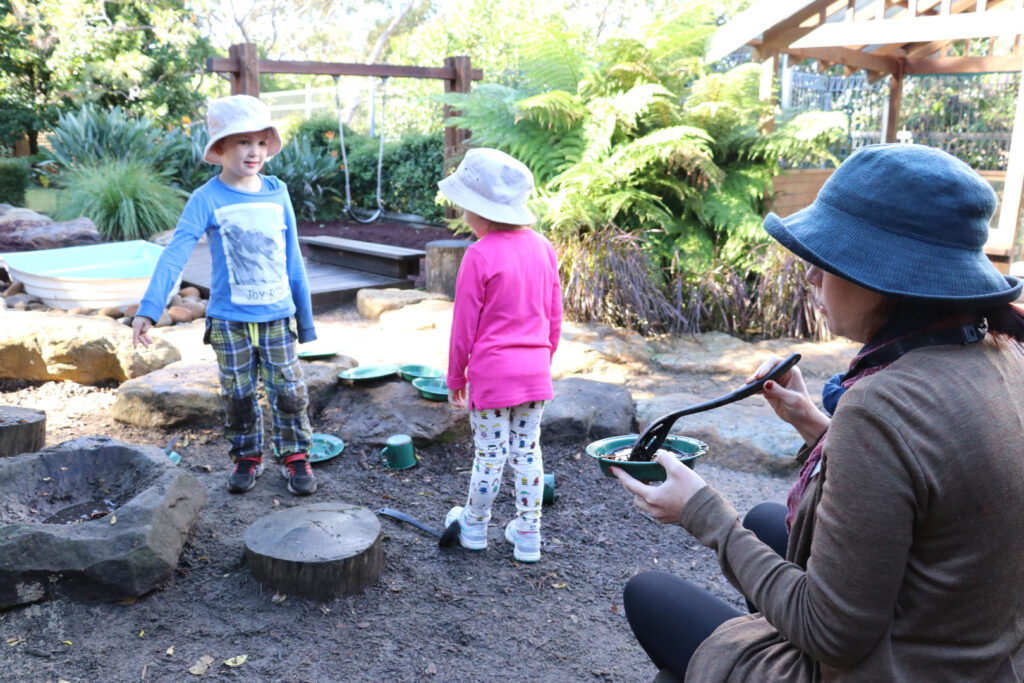 KU Castlecrag childcare educator and children playing outdoors