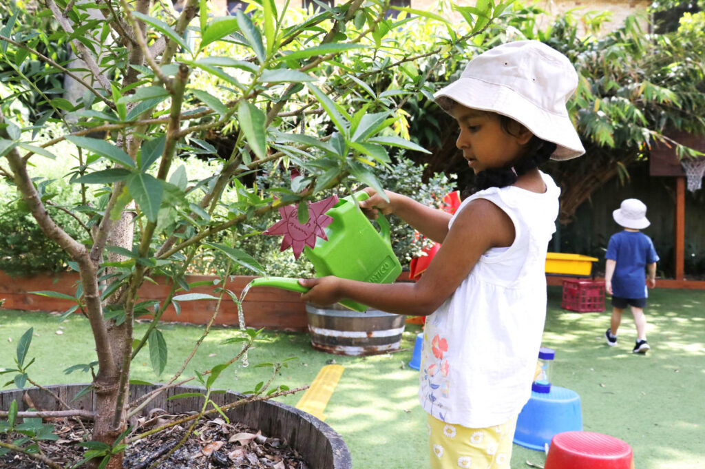 Child watering the plants at KU Chatswood Community childcare