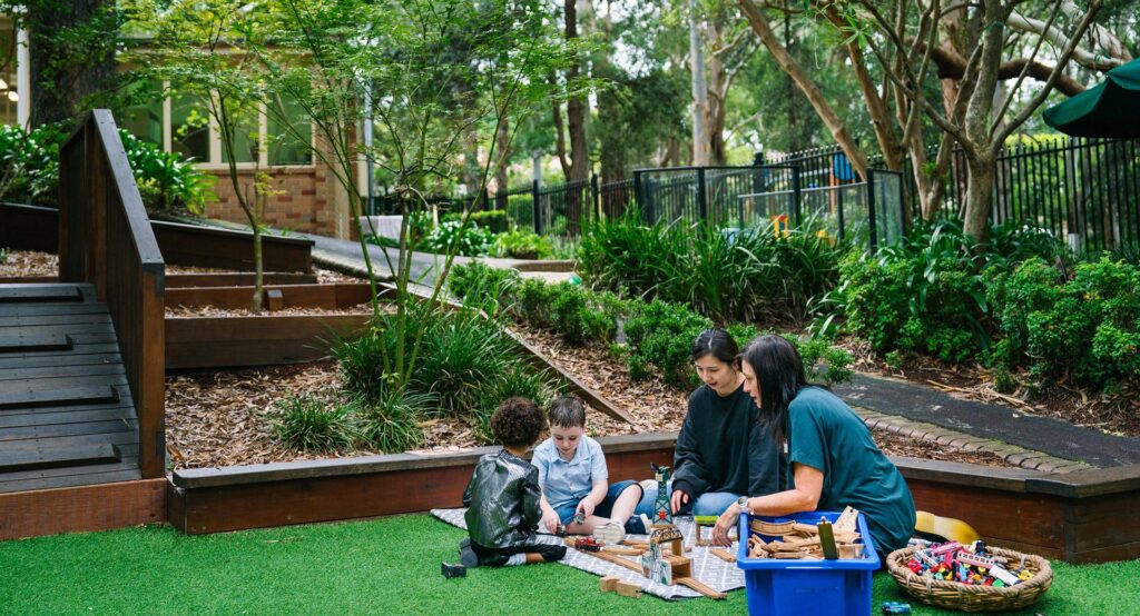 KU Chatswood West childcare educators with children playing outdoors