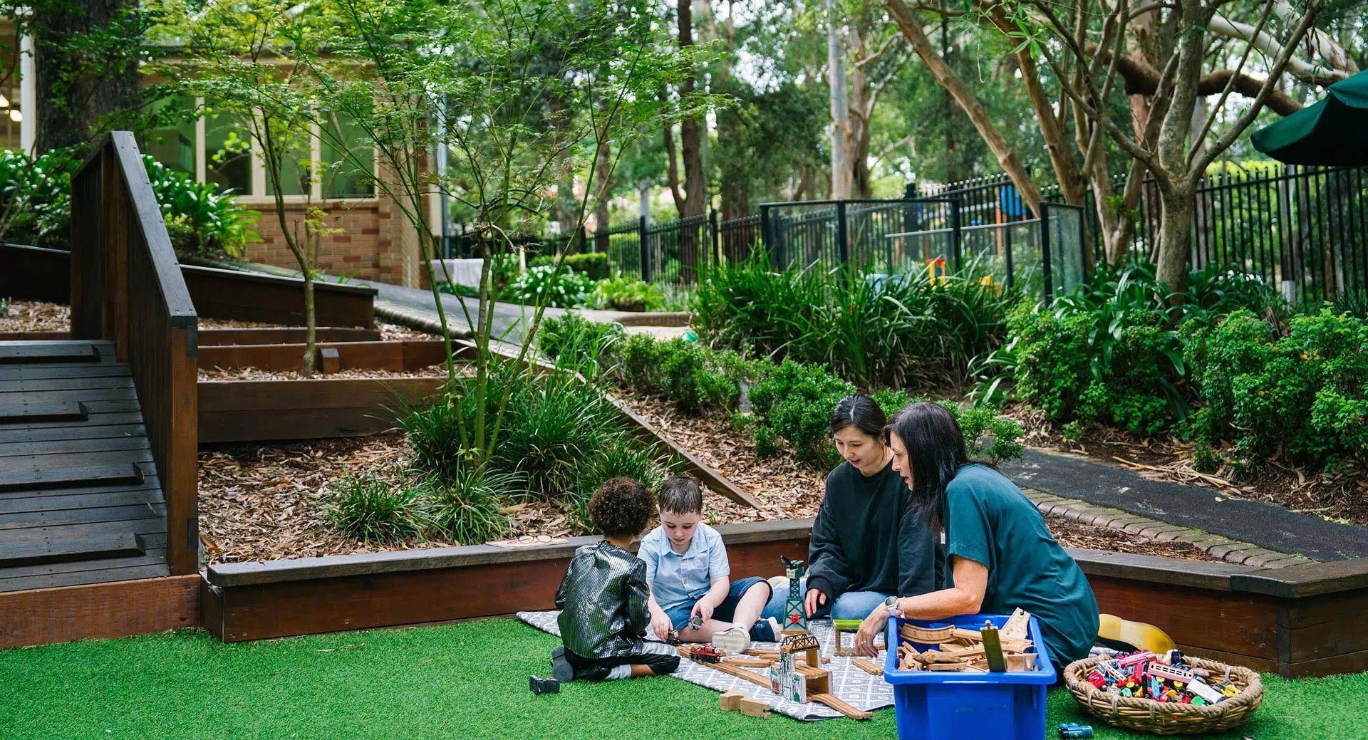 KU Chatswood West childcare educators with children playing outdoors