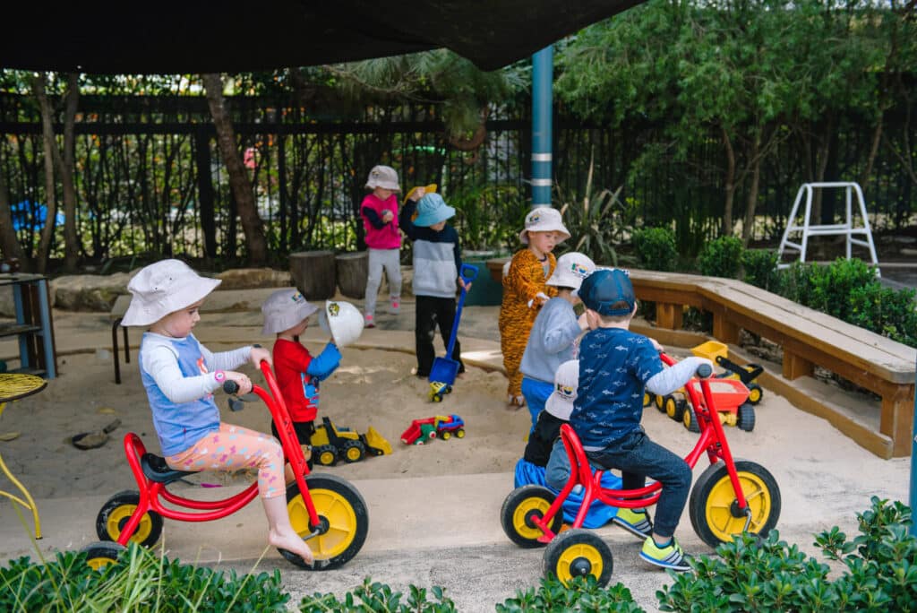 Children riding tricycles at KU Cobbitty childcare