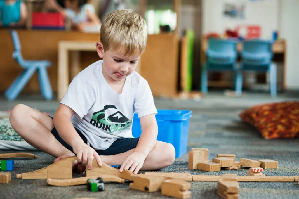 Child playing with train sets at KU Corrimal East childcare