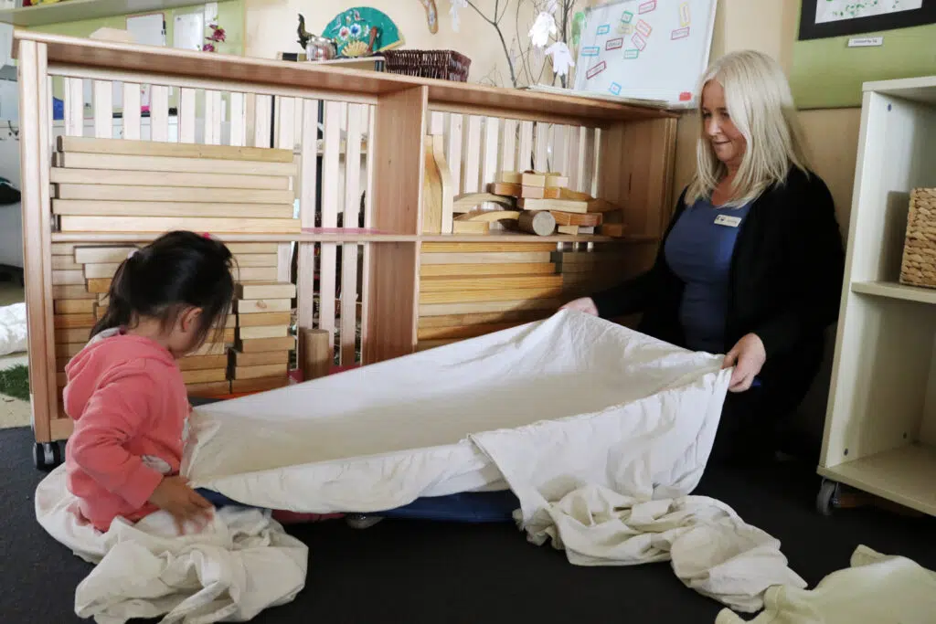 KU Craigieburn childcare educator building a blanket fort with a child