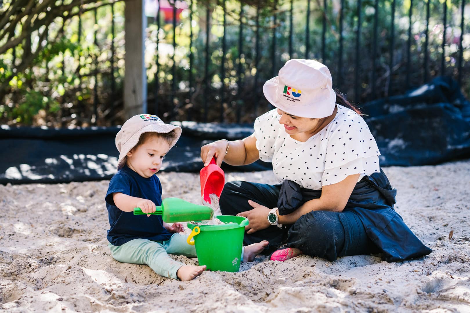 Educator interacting with child in sandpit at KU Craigieburn Childcare