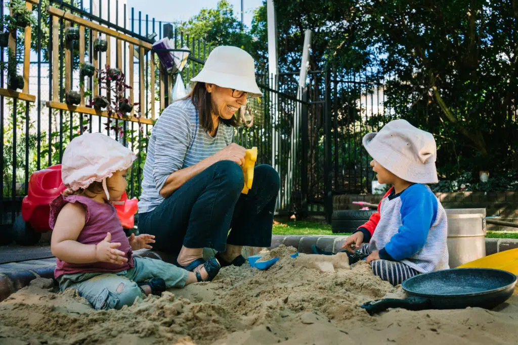 KU Union childcare educator and some children in the sand