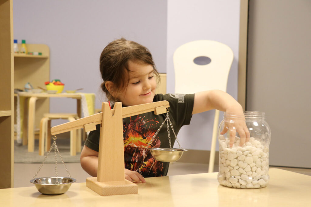 A child playing with balance scales at Honey Bird Childcare
