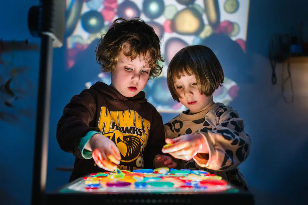 Children playing with translucent shapes on a lightbox at KU Monash childcare