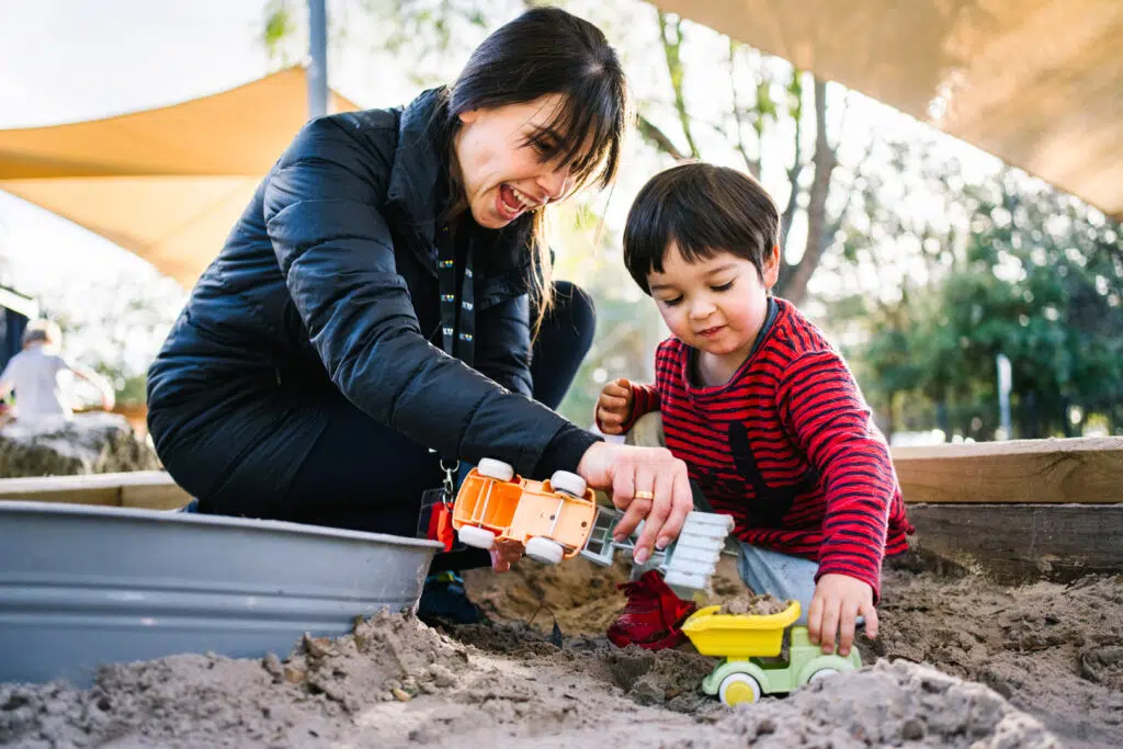 KU Monash childcare educator and a child in the sandpit