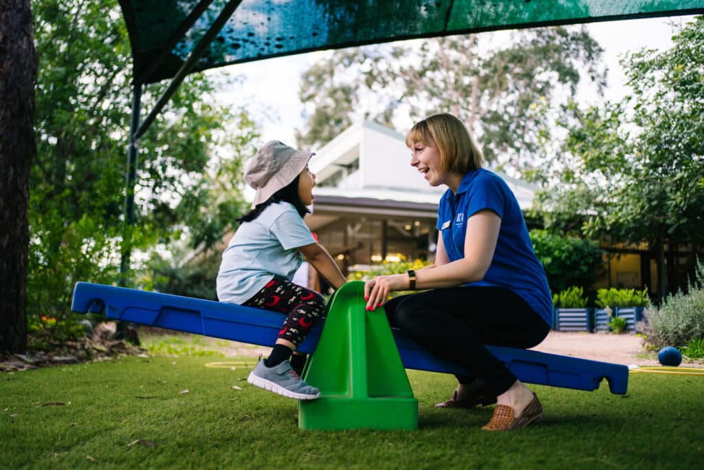KU Hebersham childcare educator and child on a seesaw