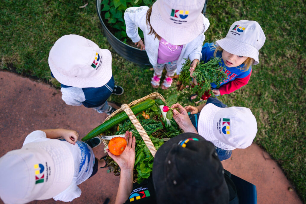 KU Kahibah Road childcare educator and children in a vegetable garden