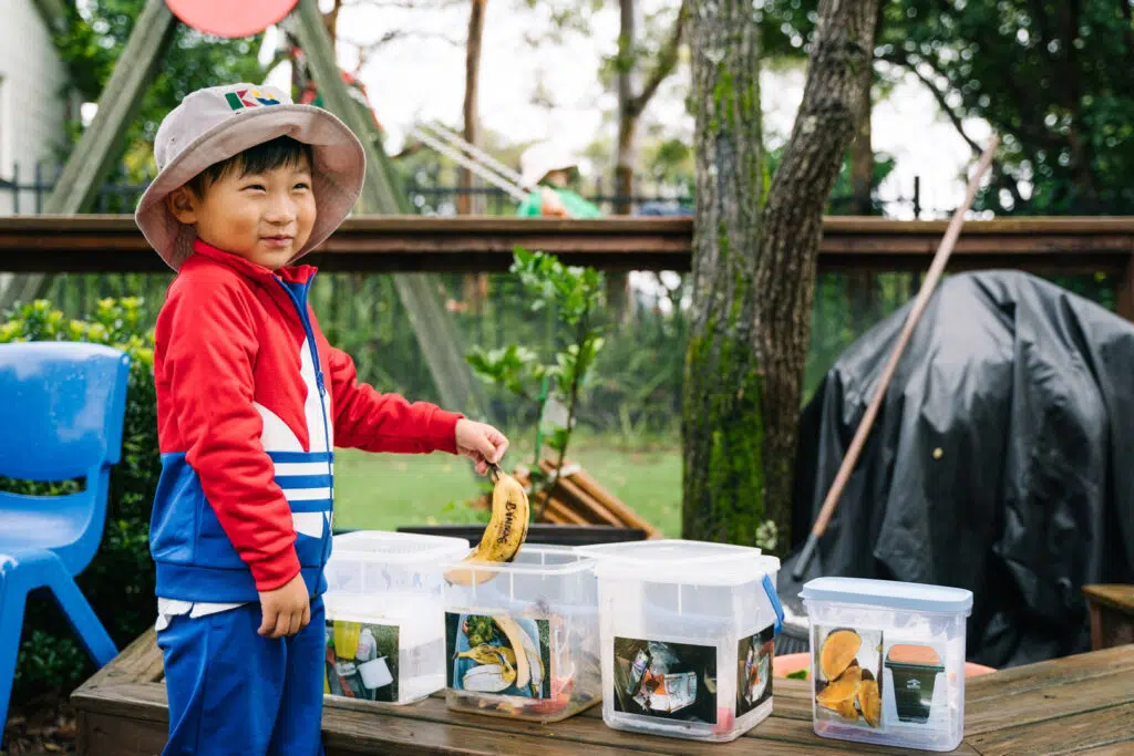 Child using a compost bin at KU Grevillea childcare