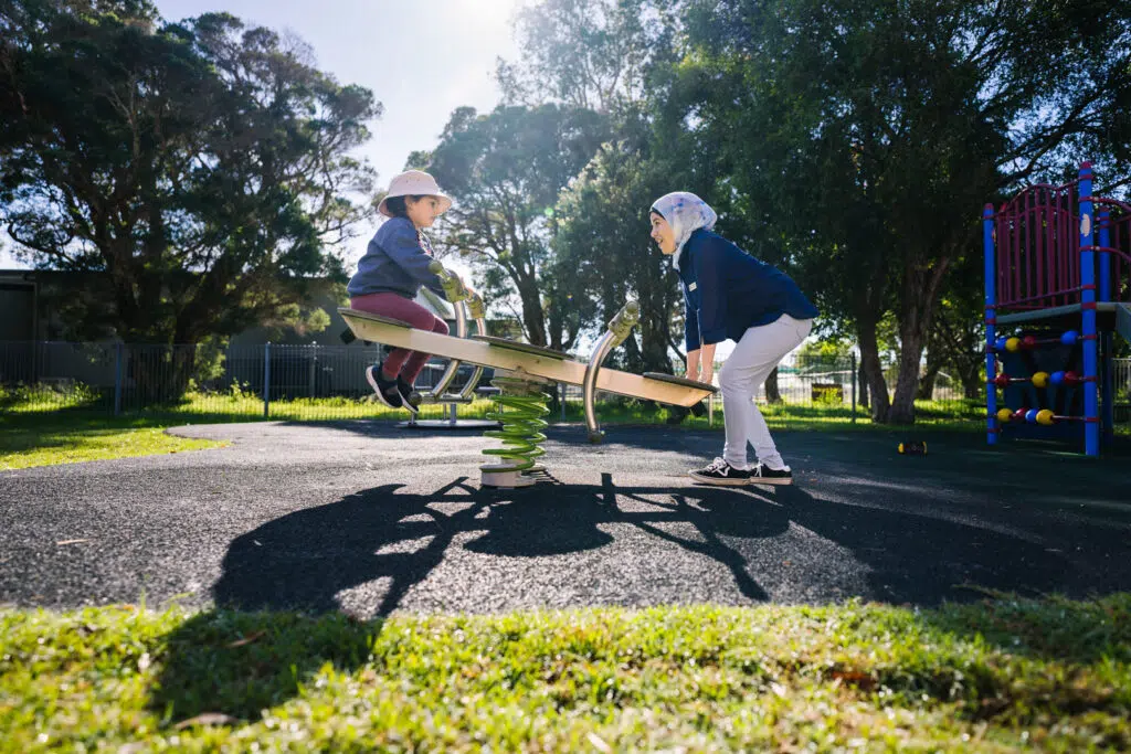 KU NSP Jesmond Neighbourhood childcare educator and a child on the seesaw