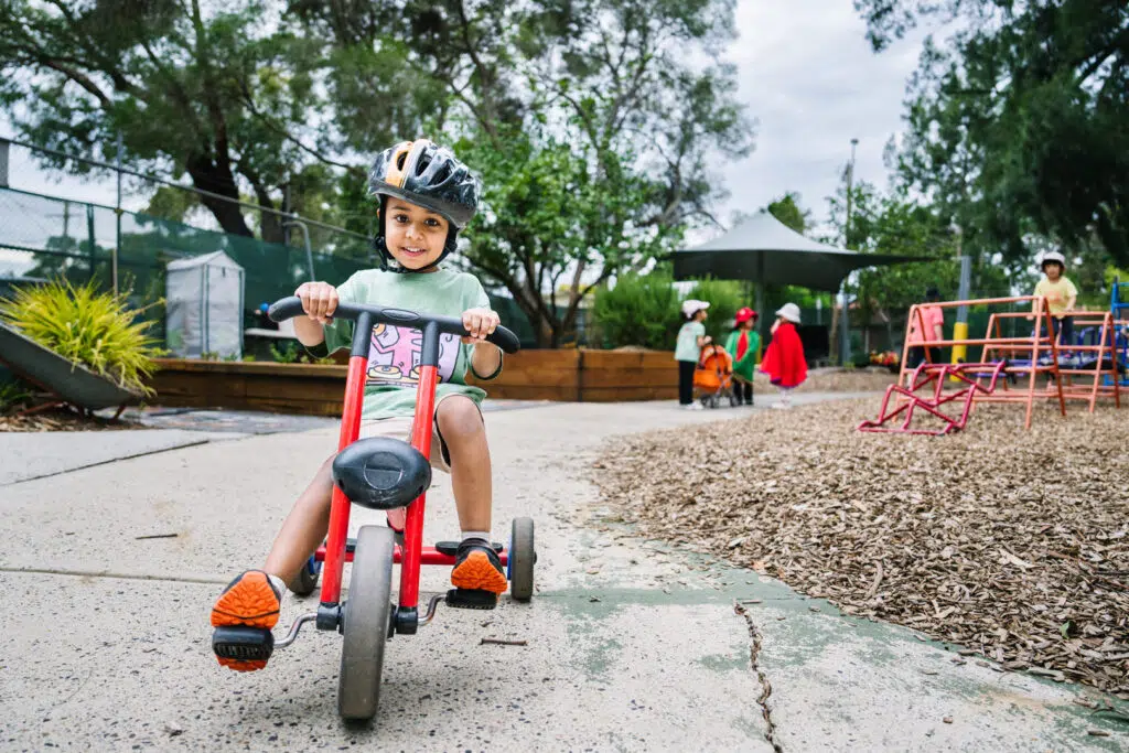 Child riding bike at KU Knoxfield childcare