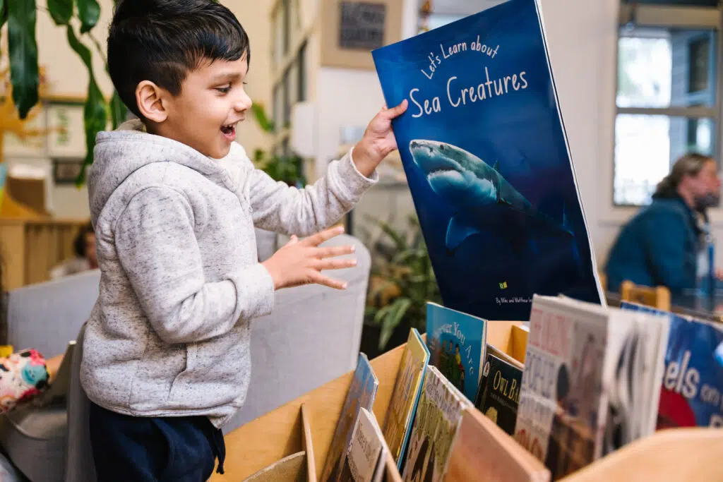 Child selecting a book to read at KU Liverpool childcare