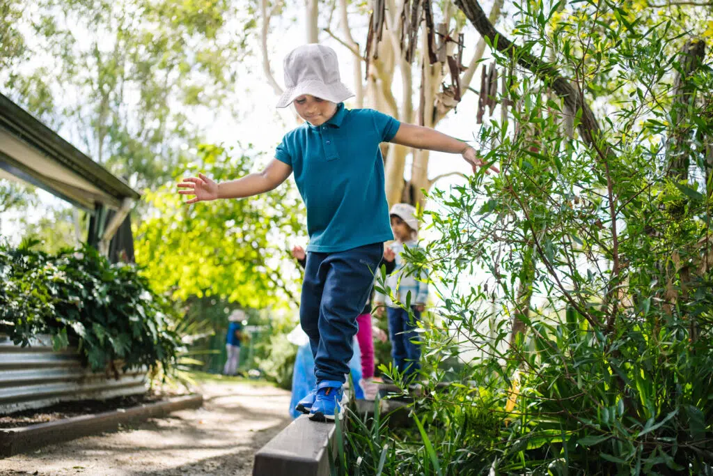Child balancing on a wooden plank at KU Macquarie Fields childcare