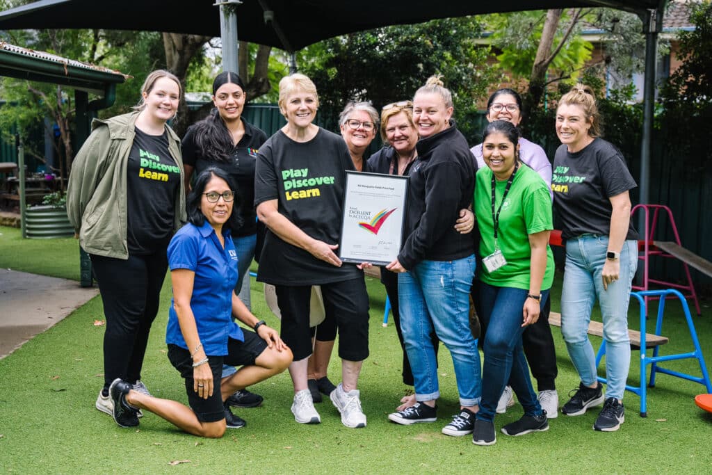 KU Macquarie Fields childcare educators standing together holding the framed excellent rating by ACECQA