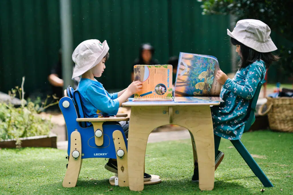 Children reading outdoors at KU Macquarie Fields childcare