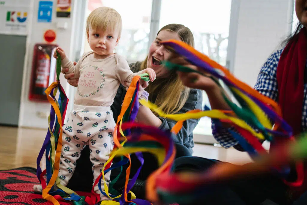 KU NSP Maryland Public School childcare educator with a child playing with ribbons