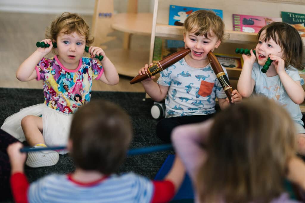 Children playing with aboriginal clapping sticks at KU Lance childcare