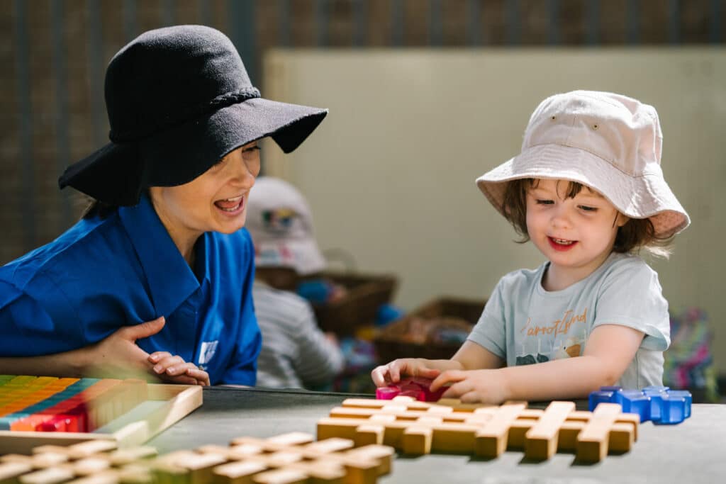 KU Lance childcare educator and a child doing a block puzzle