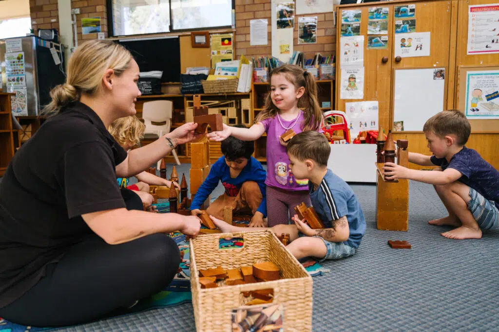 KU Milperra childcare educator and children playing with wooden blocks