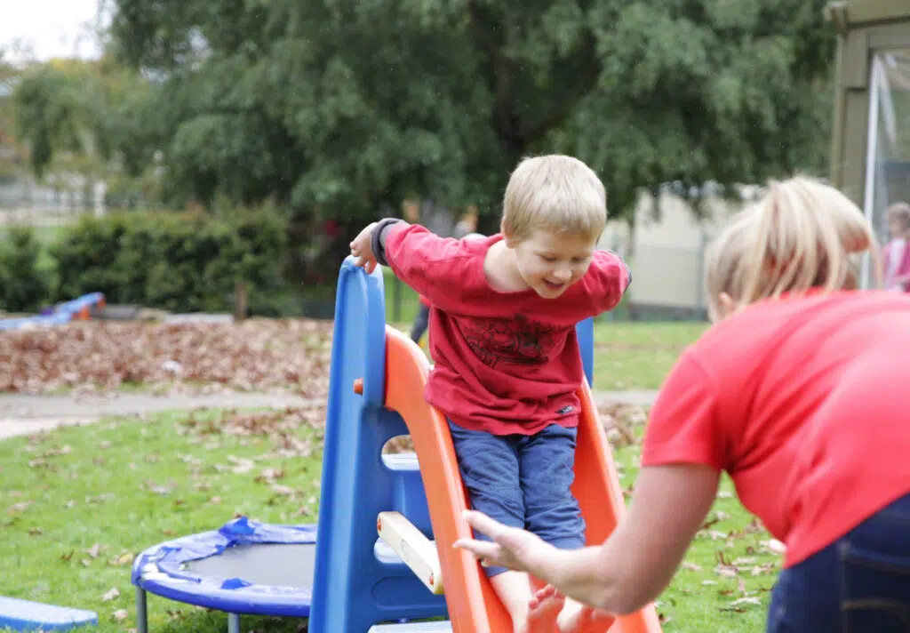 KU Moss Vale childcare educator assisting a child on the slide