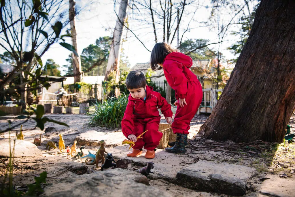 Children playing with dinosaurs outdoors at KU Bilya Gulyangarri