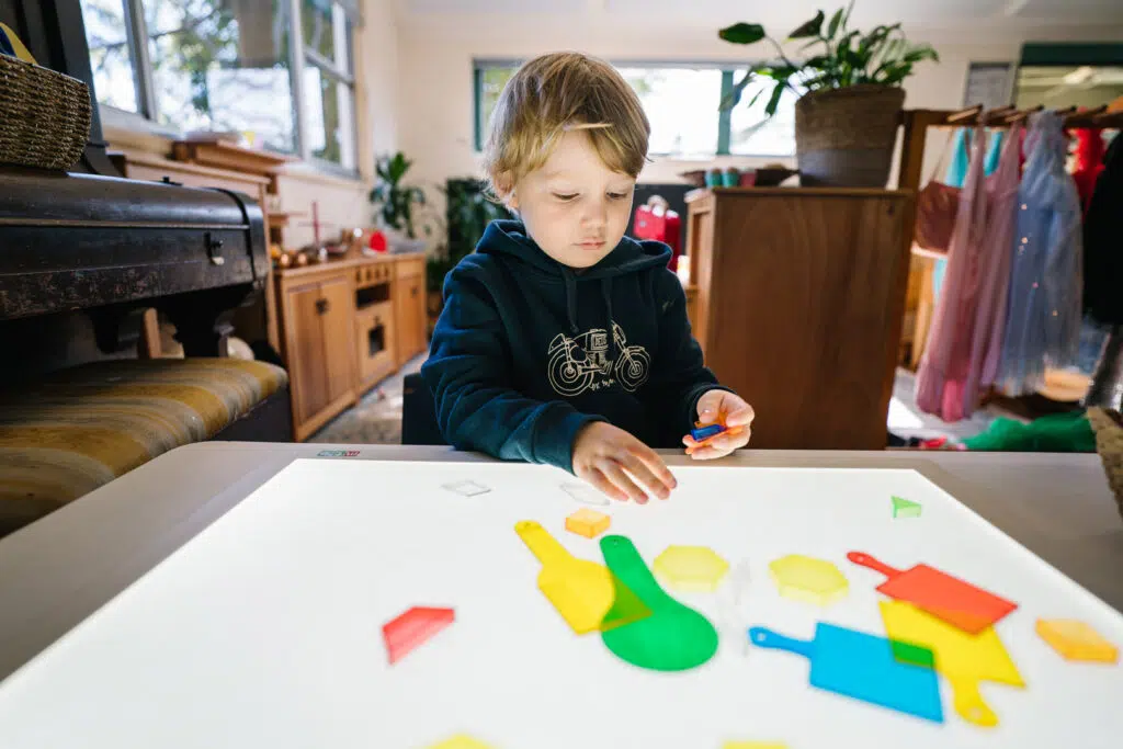 Child playing with translucent shapes at KU Peter Pan Paddington childcare