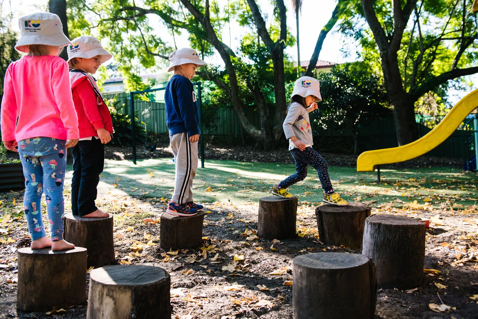 Children walking across logs at KU Padstow childcare
