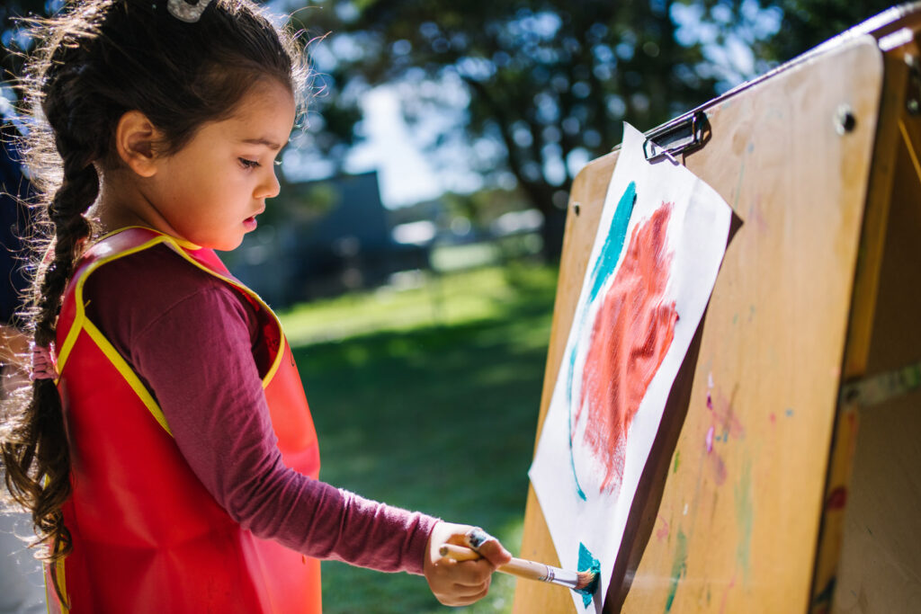 Child painting at KU NSP Shortland Public School childcare