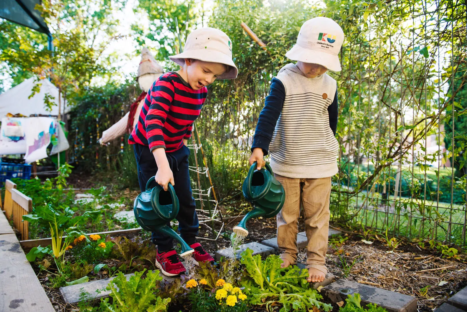 Children watering a garden at KU Henson Street childcare