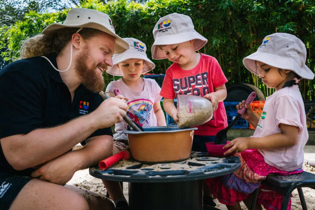 KU Phillip Park childcare educator and children playing with sand