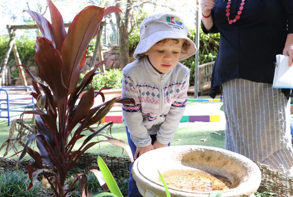 Child looking at a birdbath at KU Fox Valley childcare