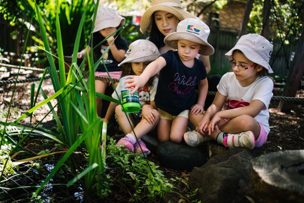 KU Bradfield Park childcare educator supervising some children feeding fish