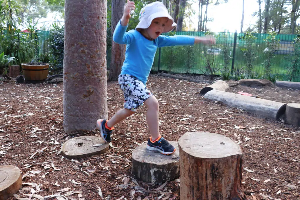 Child hopping from log to log at KU West Pymble childcare
